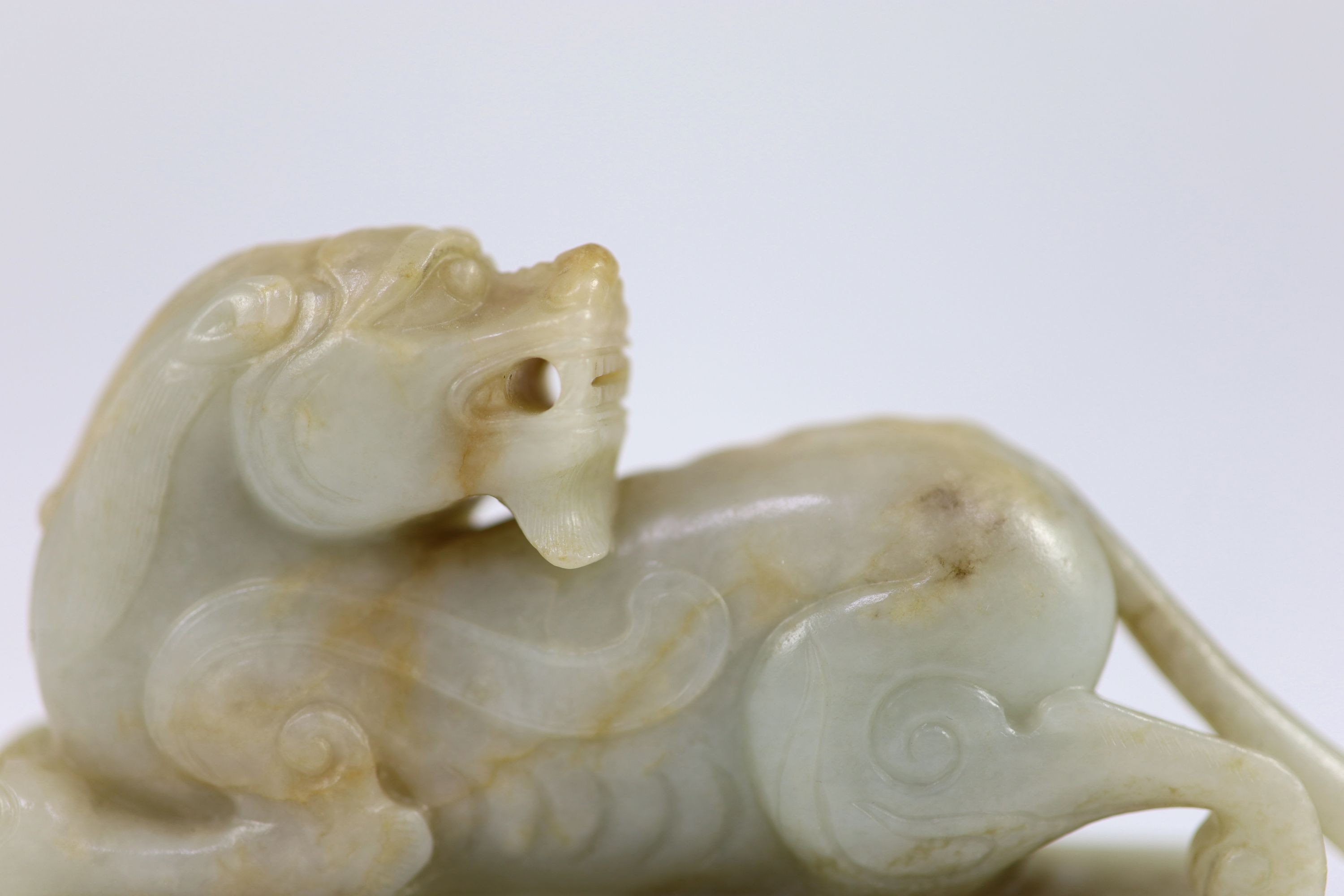 A Chinese Ming archaistic pale celadon and russet jade figure of a pixiu, 16th/17th century, 11.5cm long
